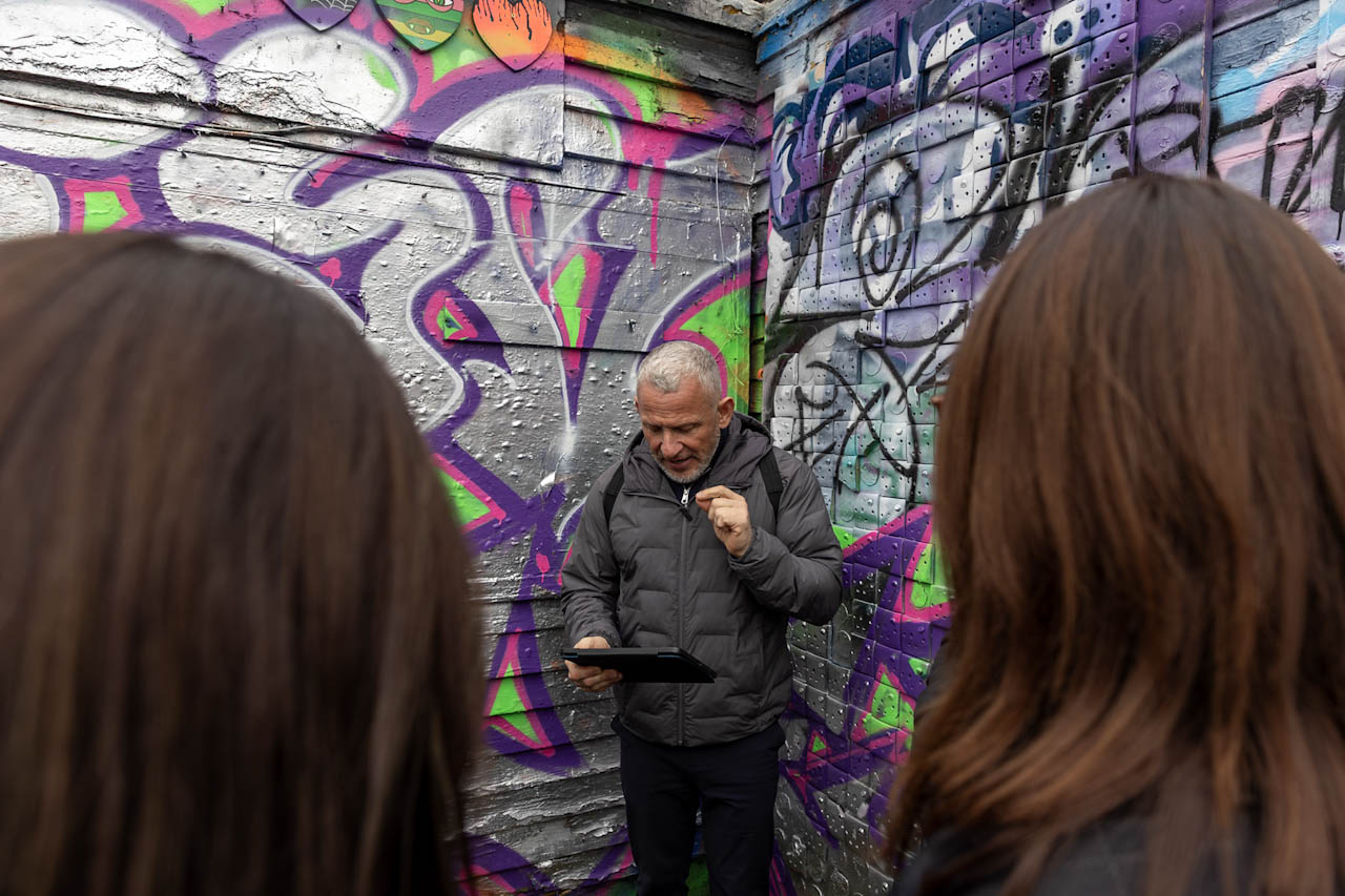 Guests listening to their guide beside East London street art